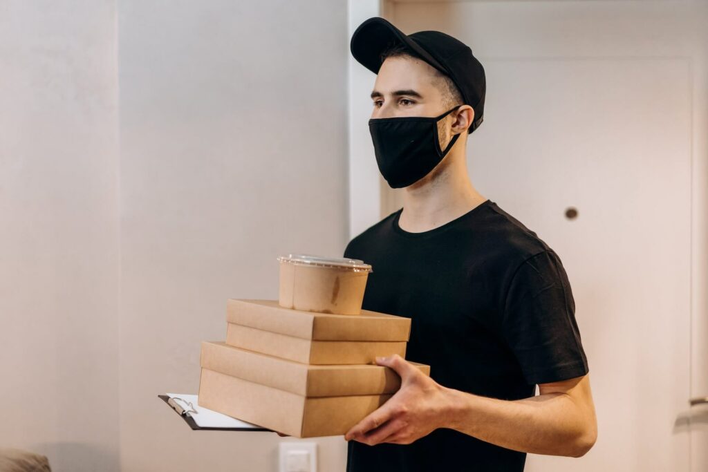 A man with a safety mask holding packages