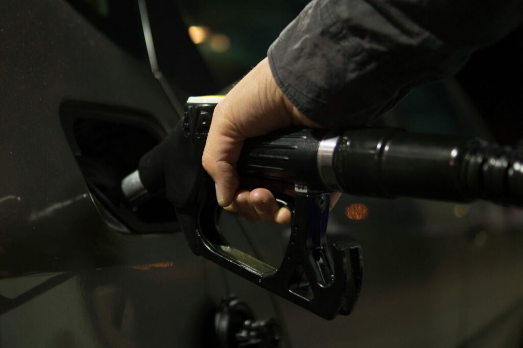 A hand holding gasoline nozzle and refilling a car