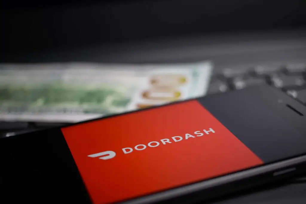 close up of mobile phone screen with logo lettering of Doordash payment provider on computer keyboard