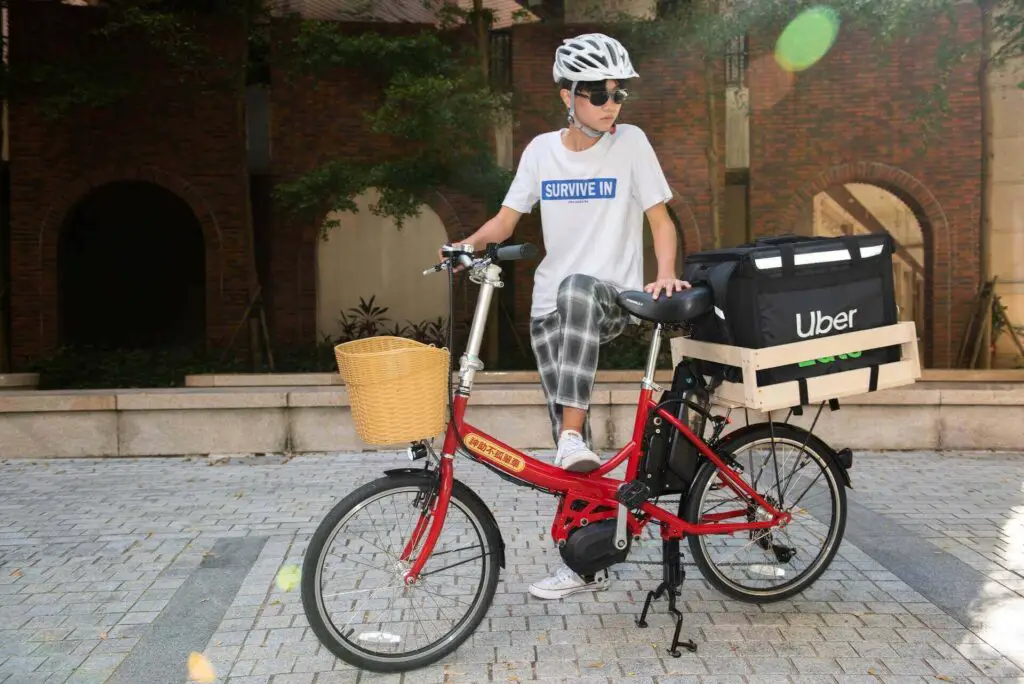 An Uber Eats food delivery guy leaning over a bicycle