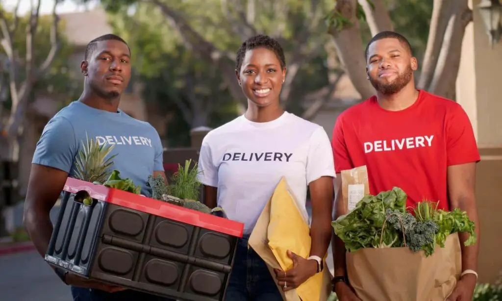 Three delivery men holding vegetables
