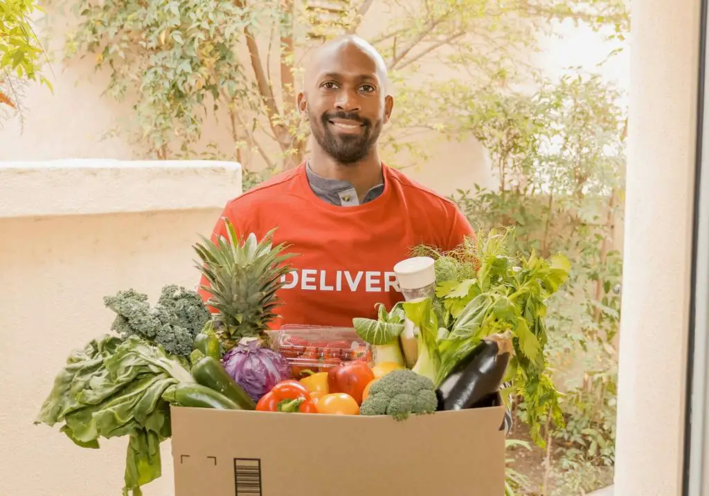 A delivery man holding a box with vegetables