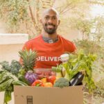 A delivery man holding a box with vegetables